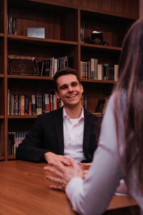 Homem simpático em entrevista de emprego com biblioteca atrás